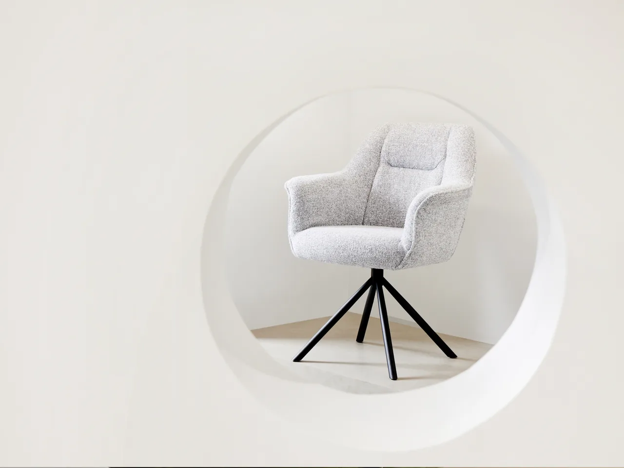 Fauteuil lounge Demu en bouclé gris clair, dossier galbé sur piètement pivotant en étoile noir